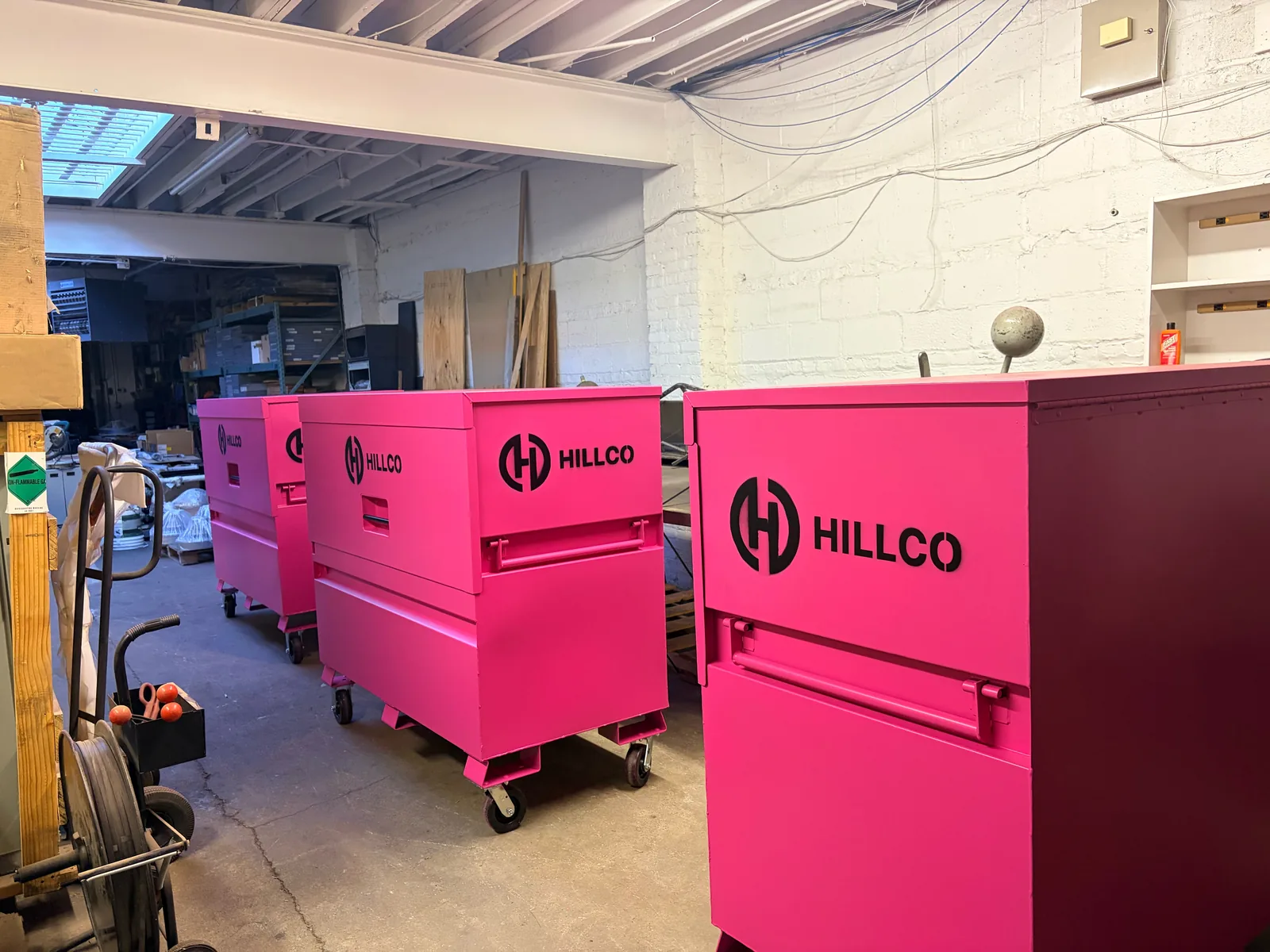 A row of pink Hillco-branded steel gang boxes lined up in a shop